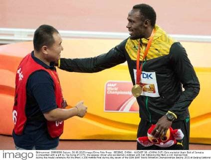 BEIJING, CHINA - AUGUST 28: (CHINA OUT) Gold medalist Usain Bolt of Jamaica is presented with a gift by Tao Song of CCTV, the segway driver who accidentally collided with him following the Men s 200 metres final, during the medal ceremony for the Men s 200 metres final during day seven of the 15th IAAF World Athletics Championships Beijing 2015 at Beijing National Stadium on August 28, 2015 in Beijing, China.  CFP471986729 