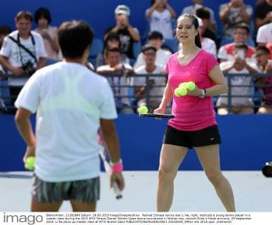 Retired Chinese tennis star Li Na, right, instructs a young tennis player in a master class during the 2015 WTA Tennis Damen Wuhan Open tennis tournament in Wuhan city, central China s Hubei province, 29 September 2015. Li Na plays up master class at WTA Wuhan Open  20150929_34421