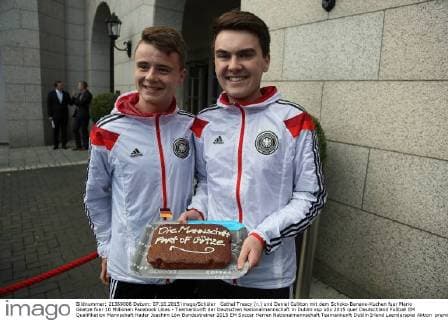 Cathal Treacy (r.) und Daniel Culliton mit dem Schoko-Banane-Kuchen fuer Mario Goetze fuer 10 Millionen Facebook Likes - Teamankunft der Deutschen Nationalmannschaft in Dublin