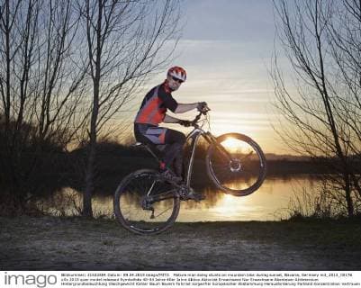 Mature man doing stunts on mountain bike during sunset, Bavaria, Germany mit_2013_00176