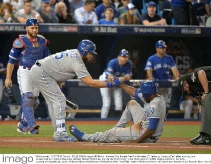 Kansas City Royals Franklin Morales (C) helps up Lorenzo Cain after scoring on a passed ball by Toronto Blue Jays catcher Russell Martin (L) during the first inning in the ALCS game 4 at the Rogers Centre in Toronto, Canada on October 20, 2015.  TOR2015102007 KEVINxDIETSCH