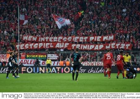 FUSSBALL CHAMPIONS LEAGUE SAISON 2014 2015 GRUPPENPHASE FC Bayern Muenchen - Arsenal London 04.11.2015 Die Bayern Fans halten ein Banner mit der Aufsachrift: WEN INTERESSIERT DIE WM TESTSPIEL AUF TRINIDAD JETZT 