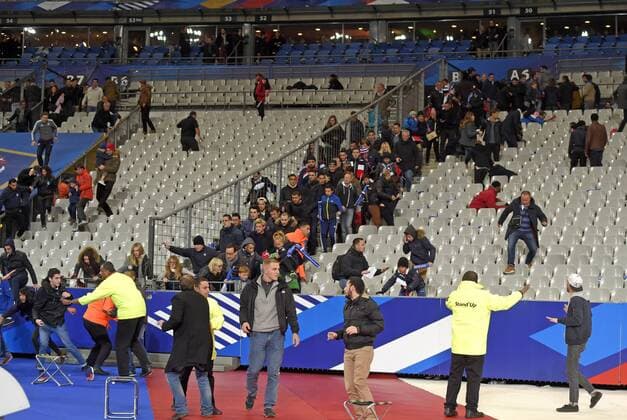 13.11.2015, Fussball Test-Länderspiel, Frankreich - Deutschland, im Stade-De-France in Paris (Frankreich), Nach dem Spiel gibt es unter den abwandernden Zuschauern plötzlich Panik wegen dem Bombananschlag und rennen panisch und voller Angst über die Sitze in den Innenraum auf den Platz um sich in Sicherheit zu bringen. Die Ordner versuchen sie noch aufzuhalten. 