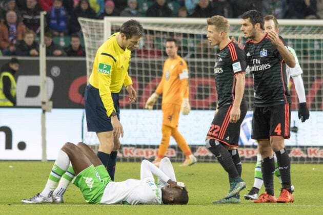Fußball, UEFA Champions League, VfL Wolfsburg - Hamburger SV; Josuha Guilavogui (Wolfsburg) angeschlagen, verletzt am Boden. Schiedrichter, Schiri, referee Wolfgang stark bei ihm. xtgx