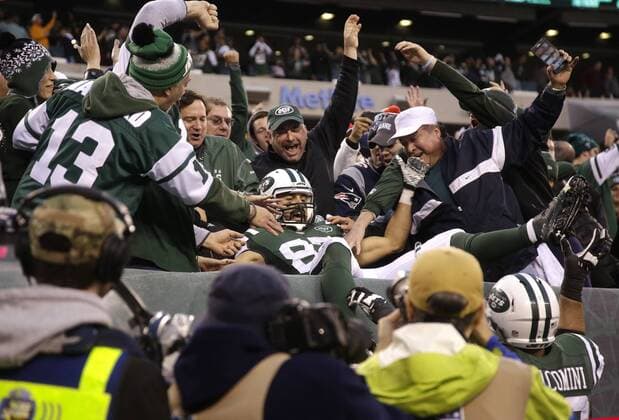 New York Jets Eric Decker leaps into the seats and celebrates with the fans after catching a 6 yard game-winning touchdown pass in overtime against the New England Patriots at MetLife Stadium in East Rutherford, New Jersey on December 27, 2015. The Jets defeated the Patriots 26-20.  NYP20151227103 JOHNxANGELILLO