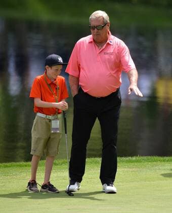 Fuzzy Zoeller helps a young patron line up a putt after he invited the child from the stands during the Par Three Contest at the 2016 Masters Tournament at Augusta National in Augusta, Georgia on April 6, 2016.  AUG20160406331 KEVINxDIETSCH