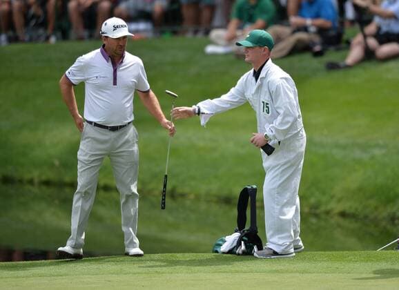 Grgraeme McDowell takes a club from his honorary caddie Army Corporal Kevin McCloskey, who lost both of his legs in a Taliban attack in 2008, during the Par Three Contest at the 2016 Masters Tournament at Augusta National in Augusta, Georgia on April 6, 2016.  AUG20160406346 KEVINxDIETSCH