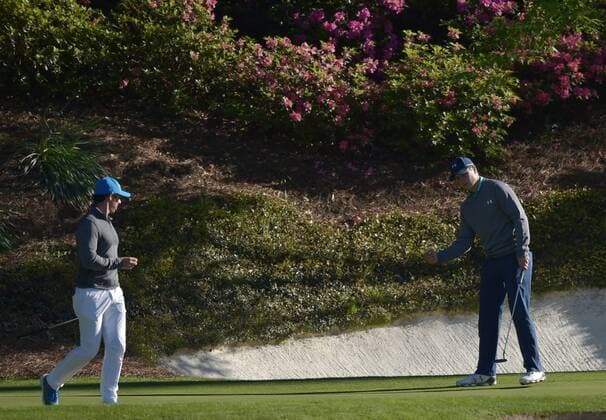 Rory McIlroy of Northern Ireland watches Jordan Spieth react after Spieth sinks a birdie putt on the 12th hole in the third round of the 2016 Masters Tournament at Augusta National in Augusta, Georgia on April 9, 2016.  MAS20160409142 KEVINxDIETSCH