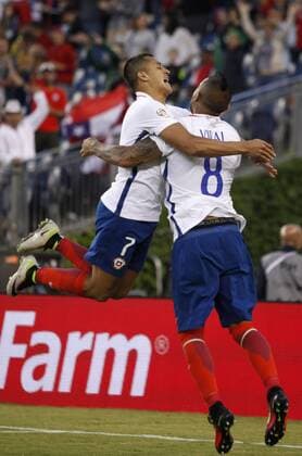Chile forward Alexis Sanchez (L) jumps into the arms of midfielder Arturo Vidal after Vidal scored in the second half of the Copa America Centenario Group D match against Bolivia at Gillette Stadium in Foxboro, Massachusetts on on June 10, 2016. Chile defeated Bolivia 2-1.  BOS2016061009 MATTHEWxHEALEY