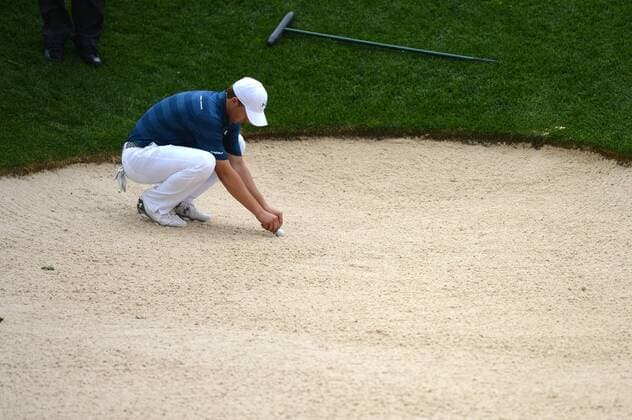 Jordan Spieth marks his ball in a bunker as the start of the second rain delay in the first round of the 2016 U.S. Open at Oakmont Country Club in Oakmont, Pennsylvania on June 15, 2016.  OAK20160616308 KEVINxDIETSCH