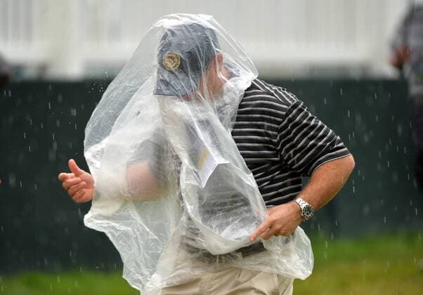 Bilder des Tages - SPORT A fan covers himself with a poncho as rain falls during the first round of the 2016 U.S. Open at Oakmont Country Club in Oakmont, Pennsylvania on June 15, 2016.  OAK20160616311 KEVINxDIETSCH