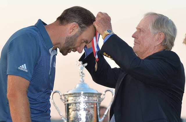 Golf Legend Jack Nicklaus puts a medal around the neck of Dustin Johnson near the Championship Trophy on the 18th green after Johnson wins his first major championship in the final round at the U.S. Open at Oakmont Country Club near Pittsburgh, Pennsylvania on June 19, 2016. Johnson won with a score of 5 under par.  OAK20160619704 KEVINxDIETSCH