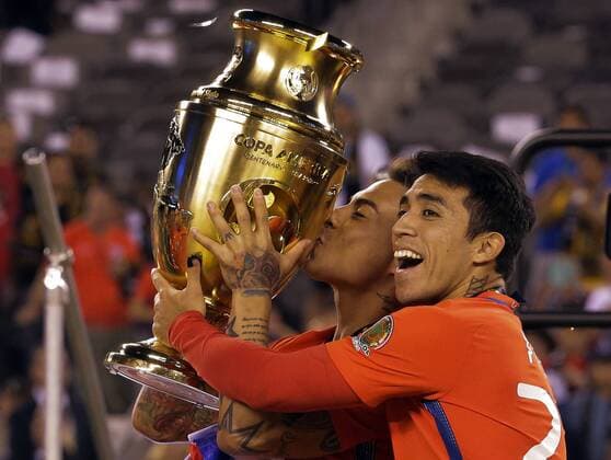 Chile forward Eduardo Vargas kisses the cup as he is hugged by midfielder Edson Puch (right) after they beat Argentina in penalty kicks 4-2 at the Copa America Centenario USA 2016 Finals at MetLife Stadium in East Rutherford, New Jersey on June 26, 2016.  NYP20160626212 RAYxSTUBBLEBINE