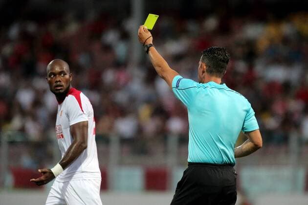 12 07 2016 Hibernians Stadium, Paola, Malta UEFA Champions League Second Qualifying Round, First Leg Valletta FC v Red Star Belgrade 1-2 Match referee Alexander Harkam (R) from the Austria FA shows the yellow card to Romeo Ramao (L) of Valletta FC during the UEFA Champions League, second qualifying round, first leg match at the Hibernians Stadium in Paola, Malta between Valletta FC and Red Star Belgrade of Serbia. Valletta FC v Red Star Belgrade - UEFA Champions League 2016 17 VALL_RSB_16