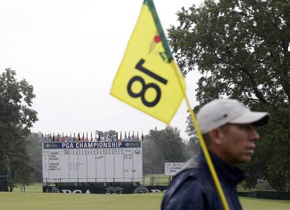 A volunteer holds the 18th hole flag and pin in the rain before play is suspended due to rain in the 3rd round at the PGA Golf Herren Championship at Baltusrol Golf Club in Springfield, New Jersey on July 30, 2016.  PGA20160730114 JOHNxANGELILLO