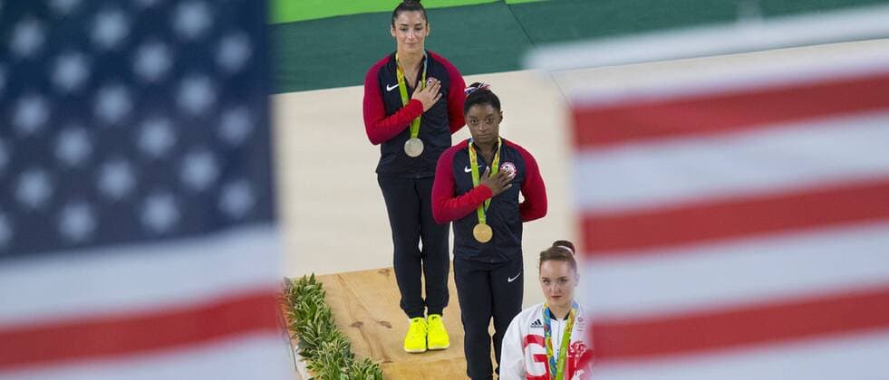 August 16, 2016 - Rio De Janeiro, BRA - Olympic Floor Exercise gold medalist Simone Biles, center, with teammate and silver medalist Alexandra Raisman, top, watch two U.S. flags raised during the medal ceremony for the event at Rio Olympic Arena in Rio de Janeiro, Brazil, on Tuesday, Aug. 16, 2016. They are joined by bronze medalist Amy Tinkler of Great Britain. Summer Olympics, gymnastics - ZUMAm67_