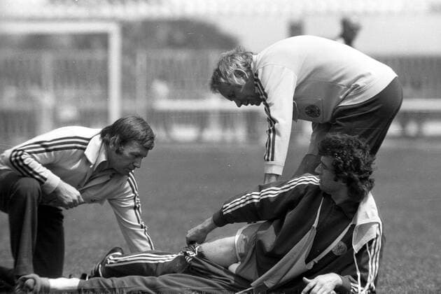 Mannschaftsarzt Prof. Heinrich Heß und Masseur Erich Deuser sehen sich die Verletzung von Bernd Cullmann (alle BR Deutschland) an