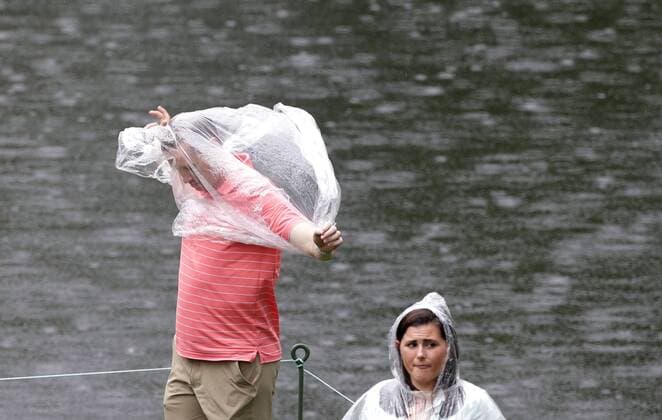 A man covers himself in a clear rain poncho after the traditional par 3 contest gets canceled due to approaching rain and thunderstorms on Wednesday at the 2017 Masters Tournament at Augusta National Golf Club in Augusta, Georgia on April 5, 2017.  AUG20170405601 JOHNxANGELILLO