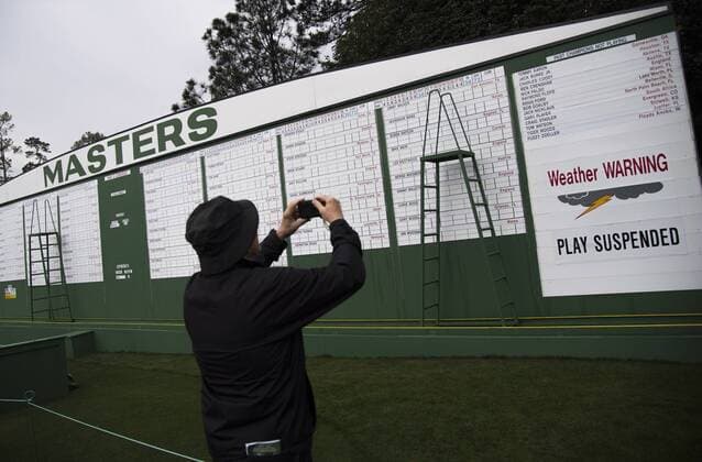 One of the final remaining patrons takes a photo of the scoreboard as he exit the grounds after the traditional par 3 contest was canceled due to approaching rain and thunderstorms on Wednesday at the 2017 Masters Tournament at Augusta National Golf Club in Augusta, Georgia on April 5, 2017.  AUG20170405302 KEVINxDIETSCH