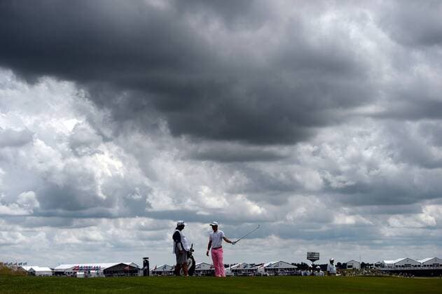 Justin Thomas (R) talks with his caddie as he waits for the group ahead on the 10th fairway during round 3 of the 117th U.S. Open golf tournament at Erin Hill golf course on June 17, 2017 in Erin, Wisconsin.  WIS20170617110 BRIANxKERSEY