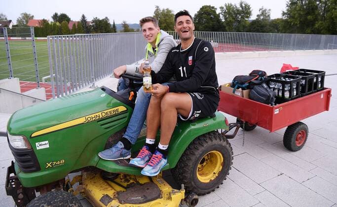 Volleyball 1. Bundesliga Saison 2017 2018 Media Day Fotoshooting TV Rottenburg 08.09.2017 Neuzugang und Spassvogel Idner Faustino Lima Martins (re) mit Apfelschorele und PR Manager Moritz Liss auf einem Rasentraktor Rottenburg