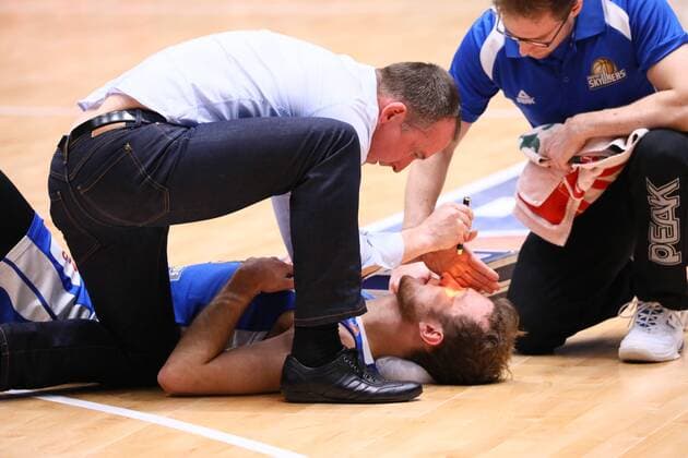 Niklas Kiel (Fraport Skyliners) ist gestürzt und wird von Teamarzt Dr. Wolfgang Raussen untersucht - 09.12.2017: Fraport Skyliners vs. Eisbären Bremerhaven, Fraport Arena Frankfurt