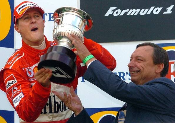 BRU443 - - FRANCORCHAMPS, BELGIUM : German Michael Schumacher celebrates as he receives his trophy from the hands of Walloon Minister of Economy Michel Daerden (R) on the podium of the Belgian Formula One Grand Prix, Sunday 29 August 2004, on the race track of Spa-Francorchamps. Finnish Kimi Raikkonen won the race and Michael Schumacher got World Champion for the 7th time. BENOITxDOPPAGNE  x2141181x
