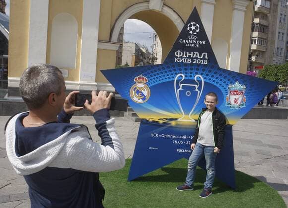May 12, 2018 - Kiev, Ukraine - People takes a photo near a large sign showcasing the logo for the 2018 UEFA Champions League Final in Kiev, Ukraine, 12 May, 2018. Kiev is preparing for the 2018 UEFA Champions League Final which will be played at the NSC Olimpiyskiy Stadium on May 26, 2018 and for the 2017-18 UEFA Women s Champions League final which will be played at Valeriy Lobanovskiy Dynamo Stadium on 24 May. 2018 UEFA Champions League Final in Kiev  - ZUMAn230 20180512_zaa_n230_569 Copyright: xStrx