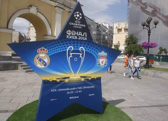 May 12, 2018 - Kiev, Ukraine - People walk past a large sign showcasing the logo for the 2018 UEFA Champions League Final in Kiev, Ukraine, 12 May, 2018. Kiev is preparing for the 2018 UEFA Champions League Final which will be played at the NSC Olimpiyskiy Stadium on May 26, 2018 and for the 2017-18 UEFA Women s Champions League final which will be played at Valeriy Lobanovskiy Dynamo Stadium on 24 May. 2018 UEFA Champions League Final in Kiev  - ZUMAn230 20180512_zaa_n230_570 Copyright: xStrx