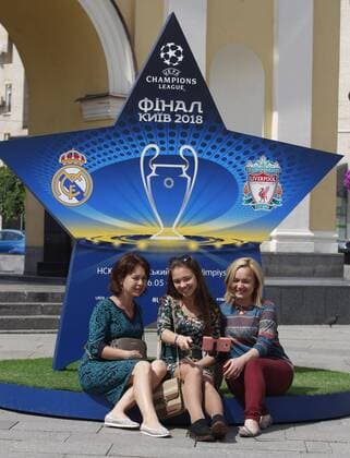 May 12, 2018 - Kiev, Ukraine - People take a selfie near a large sign showcasing the logo for the 2018 UEFA Champions League Final in Kiev, Ukraine, 12 May, 2018. Kiev is preparing for the 2018 UEFA Champions League Final which will be played at the NSC Olimpiyskiy Stadium on May 26, 2018 and for the 2017-18 UEFA Women s Champions League final which will be played at Valeriy Lobanovskiy Dynamo Stadium on 24 May. 2018 UEFA Champions League Final in Kiev  - ZUMAn230 20180512_zaa_n230_572 Copyright: xStrx