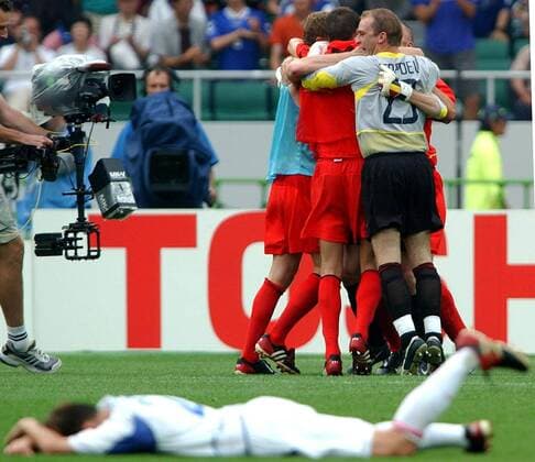 BRU10 - - SHIZUOKA, JAPAN : Players of the Red Devils Belgian national soccer team celebrate behind a dejected Russian player after winning the Group H first round last match Belgium-Russia of the 2002 FIFA World Cup WM Weltmeisterschaft Fussball in Korea and Japan, 14 June 2002 at Shizuoka Stadium. Belgium defeated Russia 3-2 and qualified for the second round. YVESxBOUCAU  x972944x