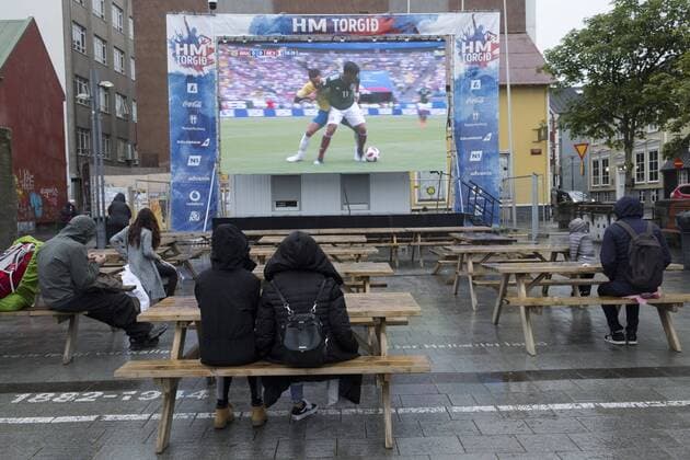Nur wenige Fußballfans verfolgen im Dauerregen das Achtelfinalspiel Mexiko gegen Brasilien anlässlich der FIFA Fussball-Weltmeisterschaft am Ingólfstorg in Reykjavik FIFA World-Cup 2018 - Public Viewing in Reykjavik