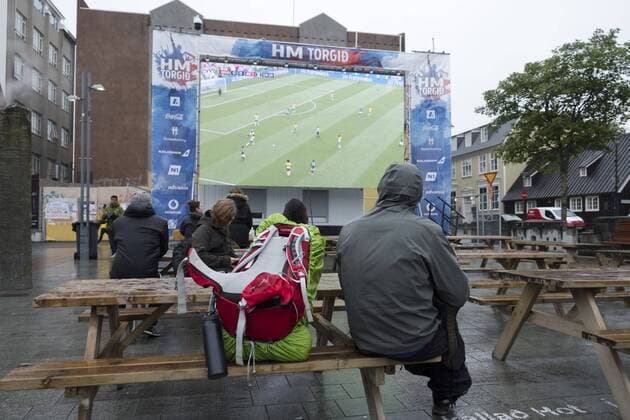 Nur wenige Fußballfans verfolgen im Dauerregen das Achtelfinalspiel Mexiko gegen Brasilien anlässlich der FIFA Fussball-Weltmeisterschaft am Ingólfstorg in Reykjavik FIFA World-Cup 2018 - Public Viewing in Reykjavik