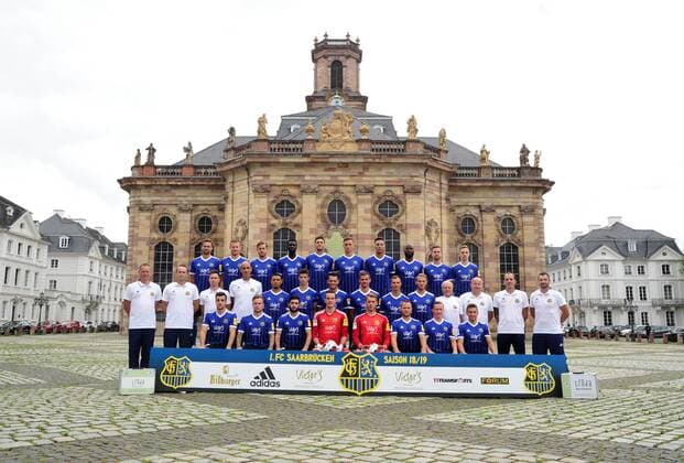 Das Team des 1. FC Saarbrücken am Donnerstag (12.07.2018) vor der Ludwigskirche in Saarbrücken. Im Bild: Obere Reihe (v.l.) Marco Holz ( 14), Macel Carl ( 22), Steven Zellner ( 5), Alexandre Mendy ( 4), Benjamin Kessel ( 15), Oliver Oschkenat ( 3), Nino Miotke ( 28), Jose Pierre Vunguidica ( 9), Sebastian Jacob ( 24) und Marco Kehl-Gomez. Mittlere Reihe: (v.l.) Robert Roelofsen (Co-Trainer), Dirk Lottner (Cheftrainer), Christoph Fuhr (Athletiktrainer), Heinz Böhmann (Torwart-Trainer), Gillian Jurcher ( 21), Lukas Quirin ( 31), Markus Obernosterer ( 10), Manuel Zeitz ( 8), Tobias Jänicke ( 25), Pierre Fassnacht ( 29), Helmut Schwan (Betreuer), Rüdiger Schmid (Zeugwart), Paulo da Palma (Physiotherapeut) und Frank Kackert (Torwart-Trainer). Untere Reihe: (v.l.) Fatih Köksal ( 27), Sascha Wenninger ( 19), Fanol Perdedaj ( 17), Ricco Cymer ( 20), Daniel Batz ( 1), Martin Dausch ( 7), Markus Mendler ( 11) und Mario Müller ( 23).