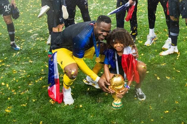 Fußball, WM Finale 2018 in Moskau, Frankreich - Kroatien 180715 Goalkeeper Steve Mandanda of France with a child celebrate with the trophy after winning the FIFA World Cup WM Weltmeisterschaft Fussball final match between France and Croatia on July 15, 2018 in Moscow. Photo: Petter Arvidson BILDBYRAN kod PA 92087 Copyright: PETTERxARVIDSON BB180715PA310
