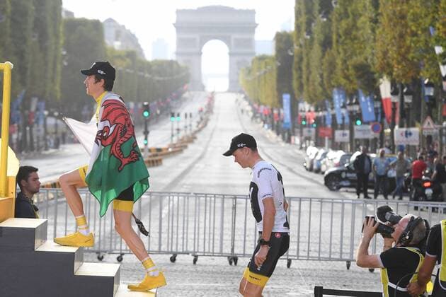 Overall winner British Geraint Thomas of Team Sky, carrying a Welsh flag and British Chris Froome of Team Sky mount the steps up to the podium with a view on the Arc de Triomphe, on the Champs Elysees, after the last stage of the 105th edition of the Tour de France cycling race, 116km from Houilles to Paris, France, Sunday 29 July 2018. This year s Tour de France takes place from July 7th to July 29th. DAVIDxSTOCKMAN  x05395072x