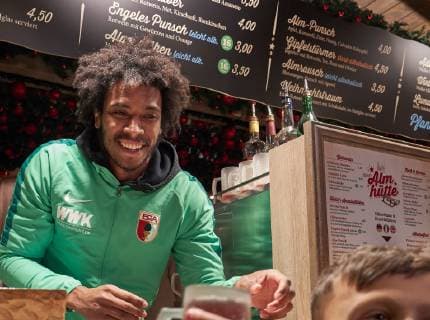 Caiuby Francisco da Silva (FC Augsburg) schenkt Glühwein aus an der Almhütte , Christkindlesmarkt Augsburg, FCA-Profis schenken Glühwein aus; Aktion Firma mit Herz für die Kartei der Not, *** Caiuby Francisco da Silva FC Augsburg presents mulled wine at the Almhütte Christkindlesmarkt Augsburg FCA professionals present mulled wine from action company with heart for the card index of the emergency