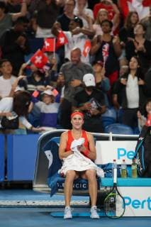 Belinda Bencic sitzt laechelnd auf dem Stuhl waehrend der Spielpause, im Hintergrund tanzen die Fans auf der Tribuene. Copyright: xJuergenxHasenkopfx