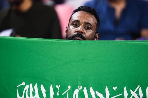 A Saudi Arabian football fan holds up his national flag to show support for Saudi Arabia national football team in the AFC Asian Cup group E match against North Korea national football team in Abu Dhabi, United Arab Emirates, 8 January 2019. Wrapped Saudi Arabian women cheer after Saudi Arabia routed North Korea 4-0 in Asian Cup  20190109_20900
