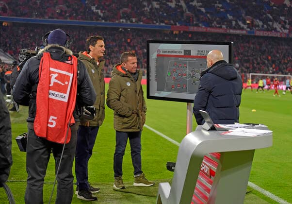 30.11.2019, Fussball 1. Bundesliga 2019 2020, 13.Spieltag, FC Bayern München - Bayer 04 Leverkusen, in der Allianz-Arena München. v.li: Sebastian Hellmann, Lothar Matthäus am SKY Expertentisch am Spielfeldrand. re: Trainer Peter Bosz (Leverkusen) an der Taktiktafel mit der Aufstellung beider Mannschaften. ***DFL and DFB regulations prohibit any use of photographs as image sequences and or quasi-video.*** *** 30 11 2019, Football 1 Bundesliga 2019 2020, 13 Matchday, FC Bayern Munich Bayer 04 Leverkusen, in the Allianz Arena Munich v left Sebastian Hellmann, Lothar Matthäus at the SKY Sports Expert Table at the edge of the field re Coach Peter Bosz Leverkusen at the tactics board with the formation of both teams DFL and DFB regulations prohibit any use of photographs as image sequences and or quasi video