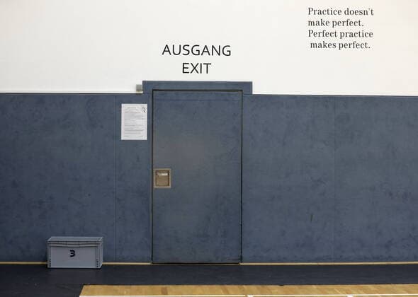 Tür im Ausbildungszentrum (ABZ) der Telekom Baskets Bonn Ausgang Eingang. Schriftzug an der Wand: practice doesn t make perfect. perfect practice makes perfect.