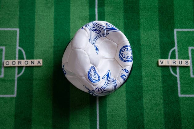 Deutschland 13.03.2020: Symbolbilder Coronavirus Das Coronavirus verursacht Veranstaltungsabsagen von Fußballspielen der Bundesligaprofiligen, Konzerte oder Schulen werden geschlossen. Hier: Ein kaputter Fußball mit dem Wort Coronavirus auf einem Fußballteppich. Deutschland