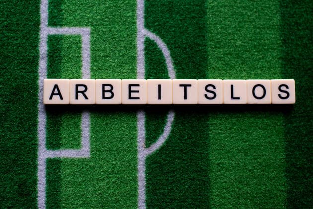 Das Coronavirus (Covid-19) verursacht Veranstaltungsabsagen von beispielsweise Fußballspielen der Bundesligaprofiligen auf unbestimmte Zeit und viele Auswirkungen, im Bild: Das Wort Arbeitslos auf einem Fußballteppich. Deutschland
