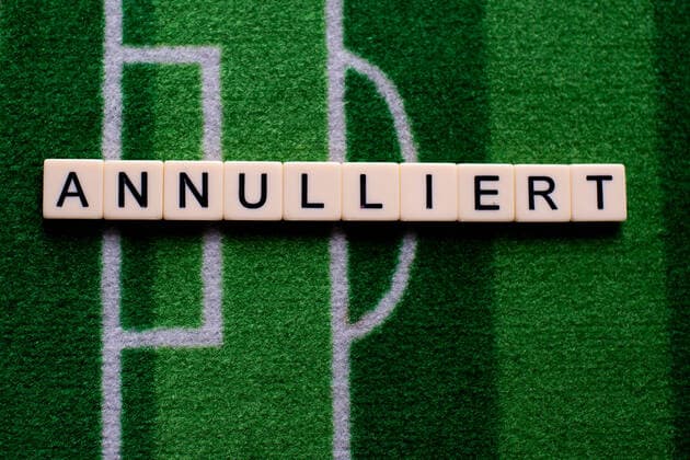 Das Coronavirus (Covid-19) verursacht Veranstaltungsabsagen von beispielsweise Fußballspielen der Bundesligaprofiligen auf unbestimmte Zeit und viele Auswirkungen, im Bild: Das Wort Annulliert auf einem Fußballteppich. Deutschland