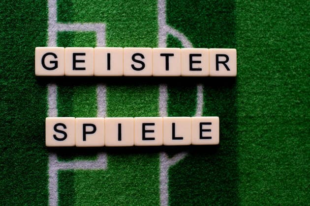 Das Coronavirus (Covid-19) verursacht Veranstaltungsabsagen von beispielsweise Fußballspielen der Bundesligaprofiligen auf unbestimmte Zeit und viele Auswirkungen, im Bild: Das Wort Geisterspiele auf einem Fußballteppich. Deutschland