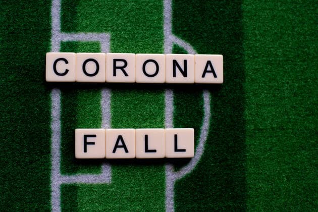 Das Coronavirus (Covid-19) verursacht Veranstaltungsabsagen von beispielsweise Fußballspielen der Bundesligaprofiligen auf unbestimmte Zeit und viele Auswirkungen, im Bild: Das Wort Corona Fall auf einem Fußballteppich. Deutschland