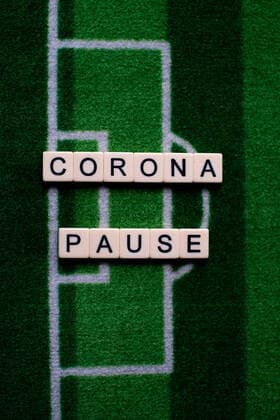 Das Coronavirus (Covid-19) verursacht Veranstaltungsabsagen von beispielsweise Fußballspielen der Bundesligaprofiligen auf unbestimmte Zeit und viele Auswirkungen, im Bild: Das Wort Corona Pause auf einem Fußballteppich. Deutschland