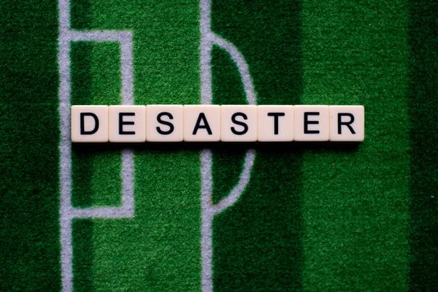 Das Coronavirus (Covid-19) verursacht Veranstaltungsabsagen von beispielsweise Fußballspielen der Bundesligaprofiligen auf unbestimmte Zeit und viele Auswirkungen, im Bild: Das Wort Desaster auf einem Fußballteppich. Deutschland