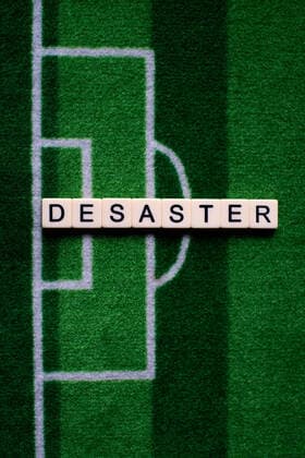 Das Coronavirus (Covid-19) verursacht Veranstaltungsabsagen von beispielsweise Fußballspielen der Bundesligaprofiligen auf unbestimmte Zeit und viele Auswirkungen, im Bild: Das Wort Desaster auf einem Fußballteppich. Deutschland