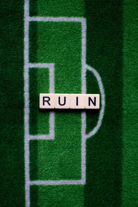 Das Coronavirus (Covid-19) verursacht Veranstaltungsabsagen von beispielsweise Fußballspielen der Bundesligaprofiligen auf unbestimmte Zeit und viele Auswirkungen, im Bild: Das Wort Ruin auf einem Fußballteppich. Deutschland